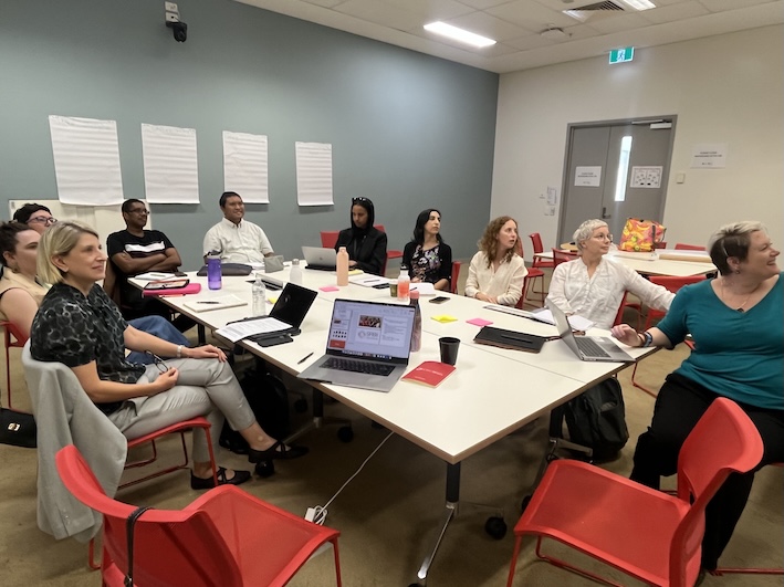 A group of people (from the SABII team) seated around a large table for a meeting.